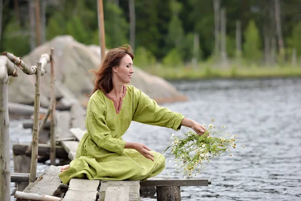 Woman by the water with a wreath in her hands — Stock Photo, Image