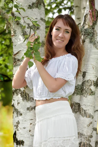 Mulher de branco por bétula no verão — Fotografia de Stock