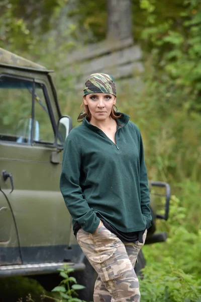 Kvinna klädd i kamouflage bandana mot bakgrund av UAZ. — Stockfoto