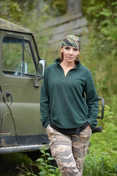Kvinna klädd i kamouflage bandana mot bakgrund av UAZ. — Stockfoto
