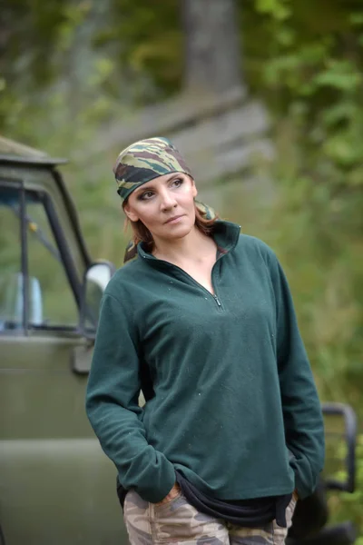 Kvinna klädd i kamouflage bandana mot bakgrund av UAZ. — Stockfoto