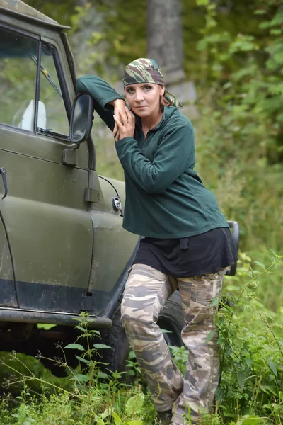 Kvinna klädd i kamouflage bandana mot bakgrund av UAZ. — Stockfoto