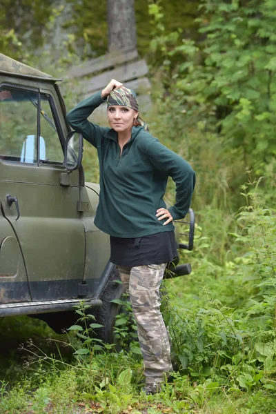 Kvinna klädd i kamouflage bandana mot bakgrund av UAZ. — Stockfoto