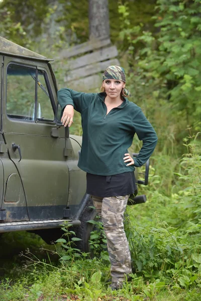 Kvinna klädd i kamouflage bandana mot bakgrund av UAZ. — Stockfoto