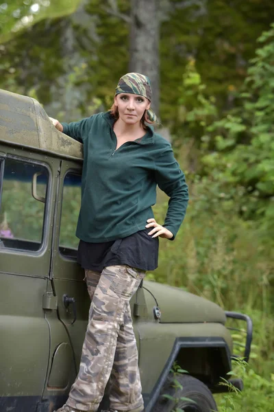 Kvinna klädd i kamouflage bandana mot bakgrund av UAZ. — Stockfoto