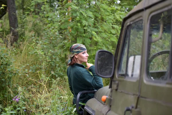 Kvinna klädd i kamouflage bandana mot bakgrund av UAZ. — Stockfoto