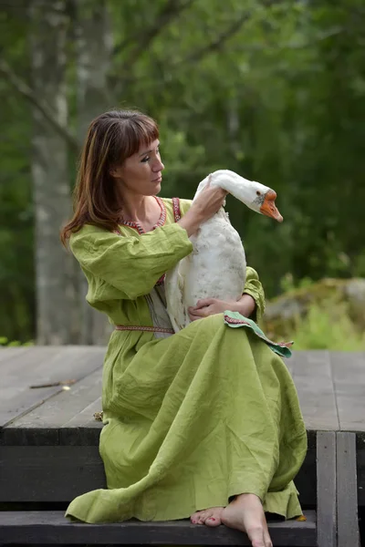 Femme en robe verte avec une oie dans les bras — Photo