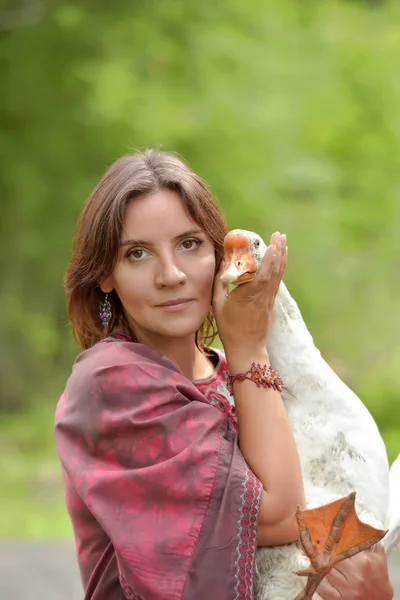 Kvinna i vinröd klänning på en gård med gås — Stockfoto