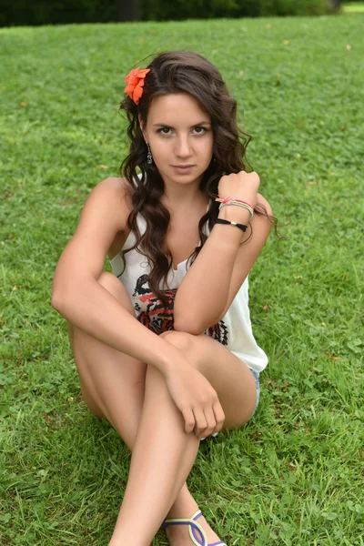 Beautiful brunette girl sitting on the lawn on the green grass i — Stock Photo, Image