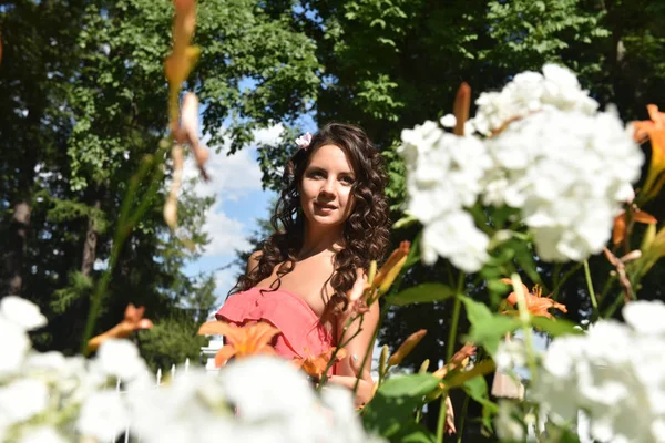 Brünette mit lockigem Haar im Sommer zwischen den Blumen — Stockfoto
