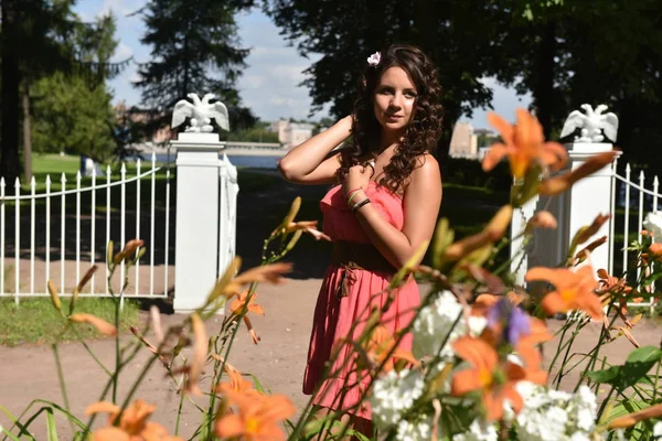 Brunett med lockigt hår på sommaren bland blommorna — Stockfoto