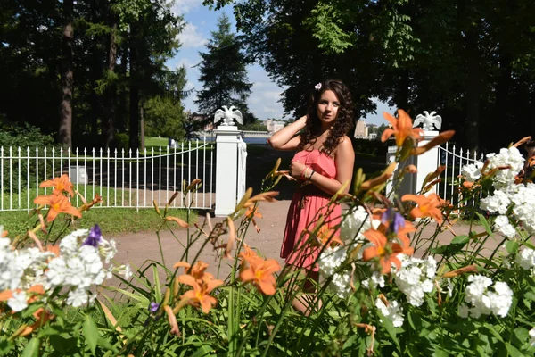 Morena com cabelo encaracolado no verão entre as flores — Fotografia de Stock