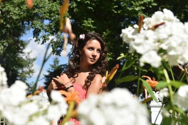 Morena com cabelo encaracolado no verão entre as flores — Fotografia de Stock