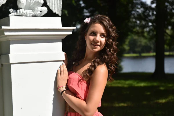 Piękna brunetka z kręcone włosy i różowy sukienka na zewnątrz — Zdjęcie stockowe