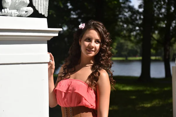 Vacker brunett med lockigt hår och rosa klänning utomhus — Stockfoto