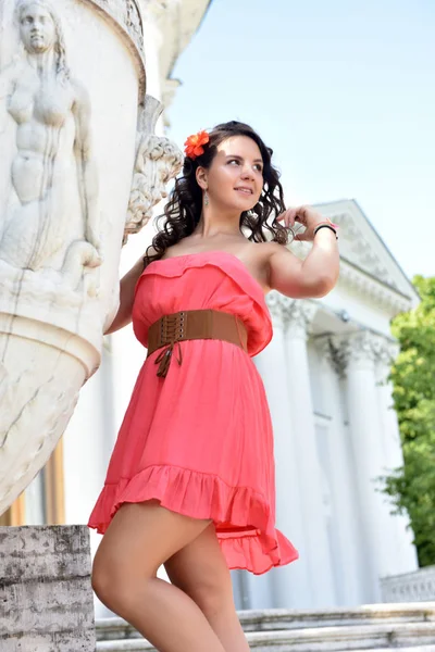 Mooie brunette met krullend haar en roze jurk buiten — Stockfoto