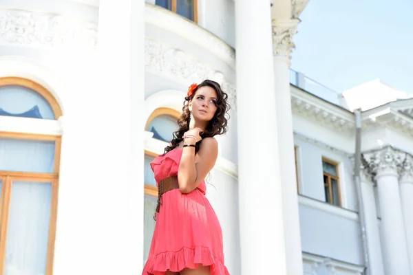 Beautiful brunette with curly hair and pink dress outdoor — Stock Photo, Image