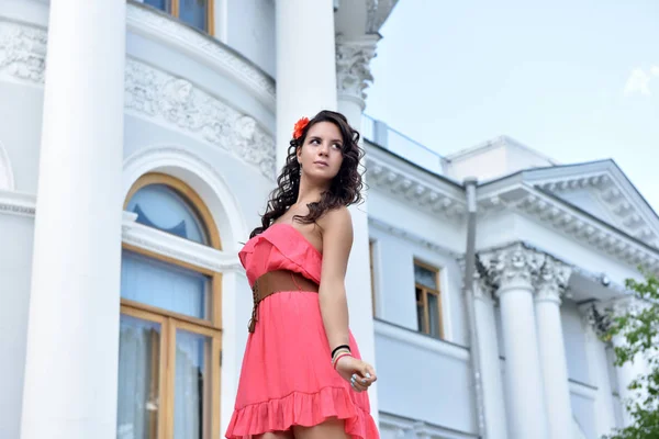 Vacker brunett med lockigt hår och rosa klänning utomhus — Stockfoto