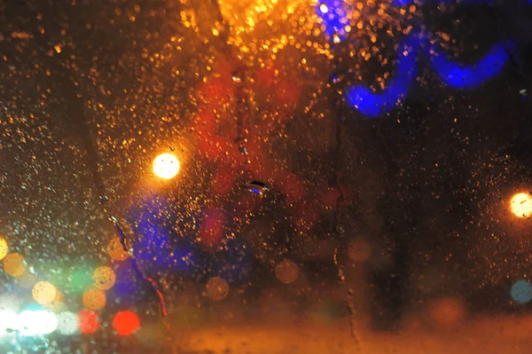 Lights at night behind glass with drops — Stock Photo, Image