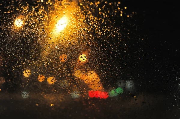 Lights at night behind glass with drops — Stock Photo, Image