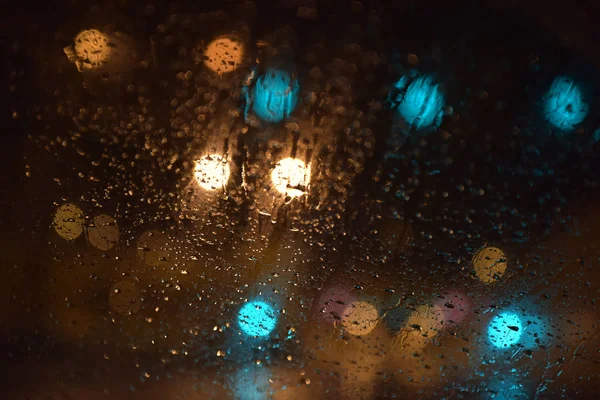 Огни ночью за стеклом с каплями — стоковое фото