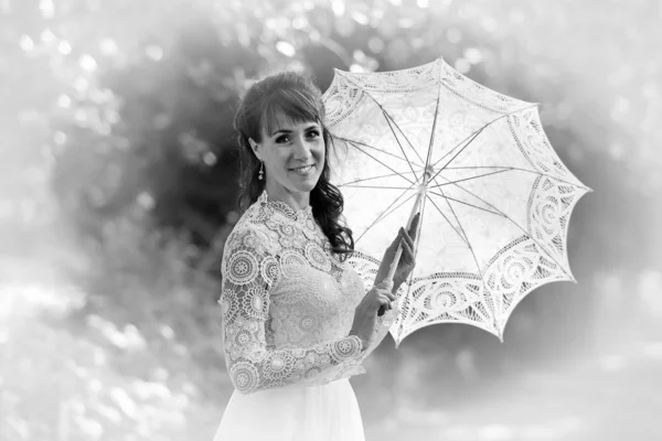 Elegante Brünette in einem weißen Kleid mit einem Regenschirm in der Mitte — Stockfoto