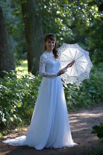 Elegante morena en un vestido blanco vintage con paraguas en th — Foto de Stock