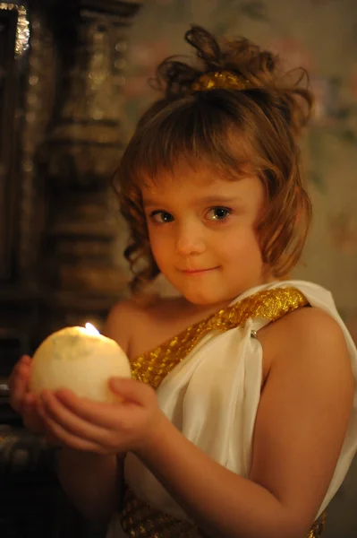 Ritratto di una bambina sorridente in tunica antica con candela — Foto Stock