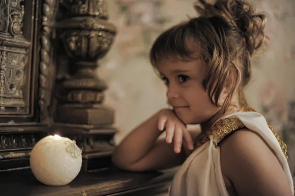 Ritratto di una bambina sorridente in tunica antica con candela — Foto Stock
