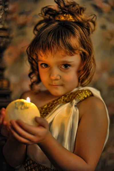 Portrait d'une petite fille souriante dans une tunique antique avec bougie — Photo