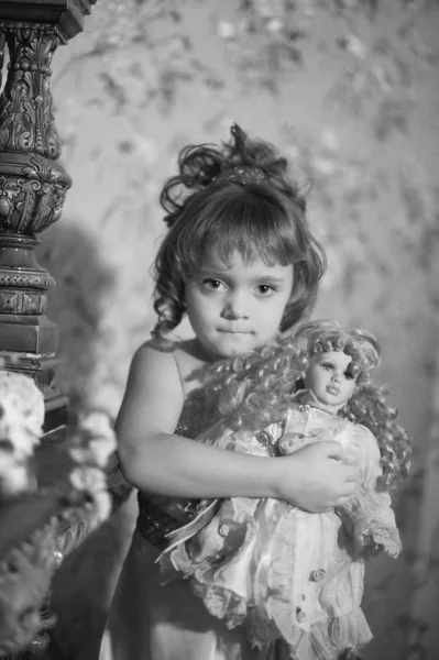 Retrato de una niña pequeña con una muñeca retro en sus manos — Foto de Stock