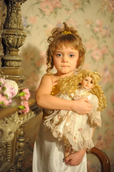 Retrato de una niña pequeña con una muñeca retro en sus manos — Foto de Stock