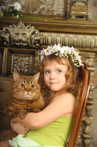 Niña sentada con una corona de flores en la cabeza con una — Foto de Stock