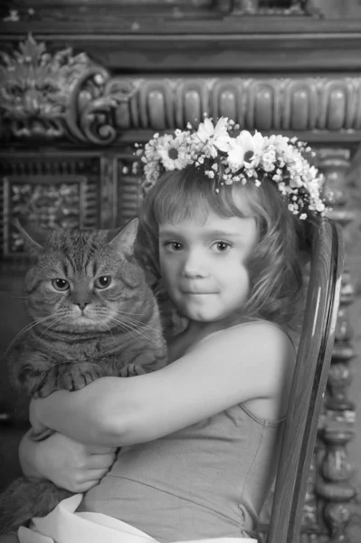 Menina sentada com uma coroa de flores na cabeça com um — Fotografia de Stock