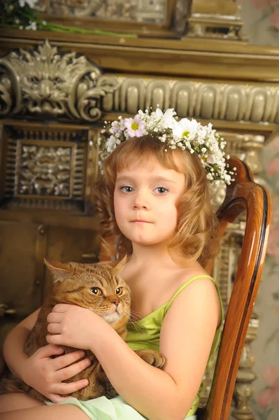 Little girl sitting with a wreath of flowers on her head with a — Stock Photo, Image