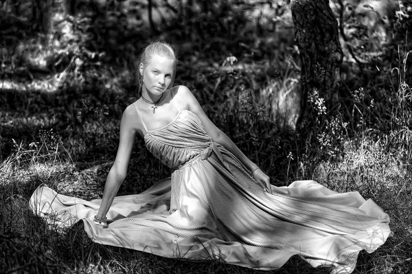 Blondynka w białej sukni siedzi na trawie, — Zdjęcie stockowe
