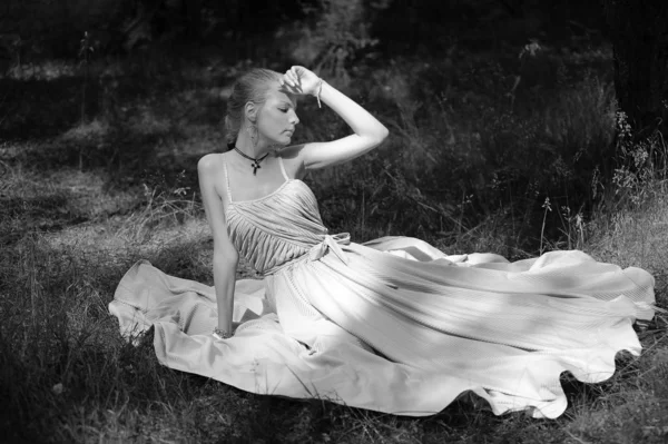 Blonde in white dress sitting on the grass, — Stock Photo, Image