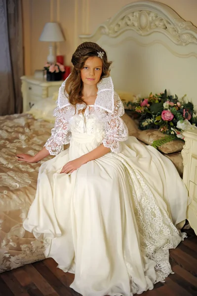 Yatakta oturan uzun beyaz elbiseli güzel kız — Stok fotoğraf