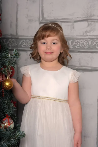 Elbiseli kız Noel ağacının yanında duruyor — Stok fotoğraf