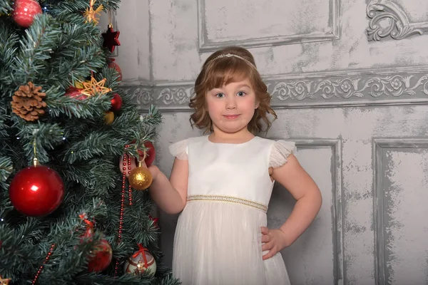 Menina de vestido fica ao lado da árvore de Natal — Fotografia de Stock