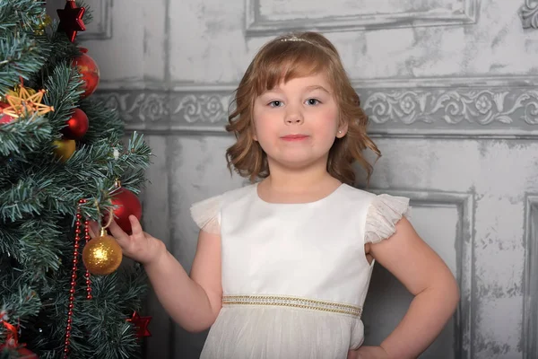 Menina de vestido fica ao lado da árvore de Natal — Fotografia de Stock