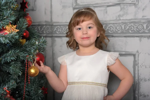 Menina de vestido fica ao lado da árvore de Natal — Fotografia de Stock