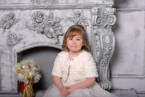 Menina em um vestido branco e um casaco de pele pela velha lareira no — Fotografia de Stock