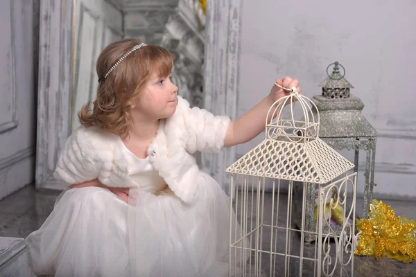 Little girl with white dress near the cell with flowers — Stock Photo, Image