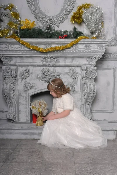Meisje in een witte jurk en een bontjas door de oude open haard in de — Stockfoto