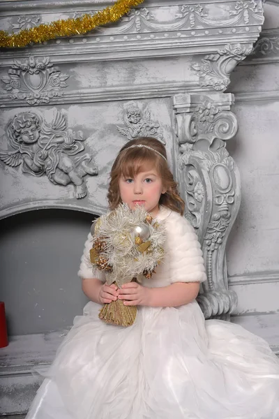 Girl in a white dress and a fur coat by the old fireplace in the — Stock Photo, Image