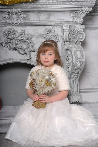 Menina em um vestido branco e um casaco de pele pela velha lareira no — Fotografia de Stock