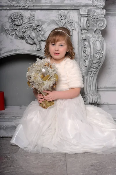 Menina em um vestido branco e um casaco de pele pela velha lareira no — Fotografia de Stock