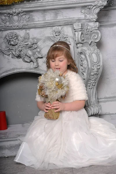 Meisje in een witte jurk en een bontjas door de oude open haard in de — Stockfoto