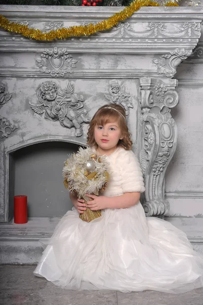 Menina em um vestido branco e um casaco de pele pela velha lareira no — Fotografia de Stock